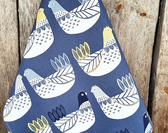 Puede incluir: Un paño de cocina azul con un patrón de pájaros blancos con acentos amarillos. Los pájaros tienen patrones geométricos y están rodeados de hojas estilizadas.