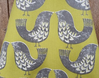Puede incluir: Una tela verde con un patrón repetitivo de pájaros estilizados grises. Los pájaros tienen acentos blancos y están delineados en negro.