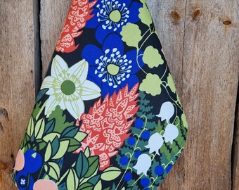 Puede incluir: Un paño de cocina negro con un patrón floral con flores rojas, blancas, azules y verdes. Las flores son estilizadas y tienen un aspecto retro.