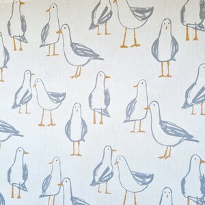 Puede incluir: Tela blanca con un patr&oacute;n repetido de gaviotas esbozadas en gris y beige. Las gaviotas se representan en varias poses, algunas de pie y otras en parejas, creando un tema costero caprichoso.