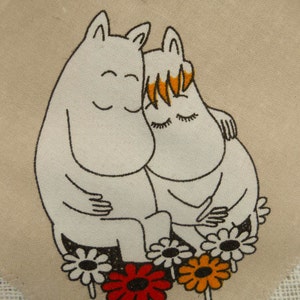 May include: Two white cartoon characters with black outlines are hugging each other. They are surrounded by five colorful flowers with black centers. The background is a beige fabric with a white lace border.