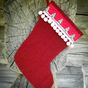 May include: A red Christmas stocking with a white pom-pom trim and a green and white patterned fabric band.