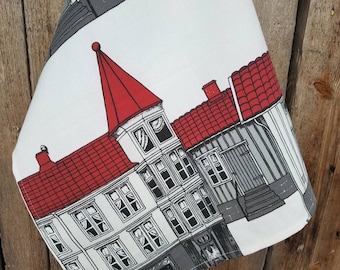 May include: A white tea towel with a black and red illustration of a row of houses with red roofs. The houses have white windows and doors. The illustration is on a white background.