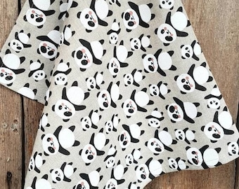 May include: A beige kitchen towel with a repeating pattern of black and white panda bears. The pandas are all facing forward with their arms raised and their eyes closed.