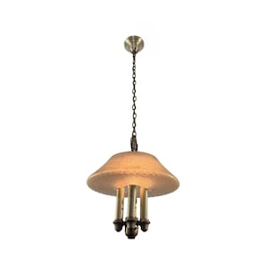 May include: An antique brass chandelier with a textured, off-white shade. The light fixture has three candle-style bulbs and hangs from a chain. The shade has a scalloped edge.