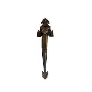 May include: A dark bronze-toned metal door handle featuring an elongated, tapered design with a textured surface. The top section has a decorative, pointed mounting plate with three circular screw holes, while the bottom ends in a small, pointed finial.