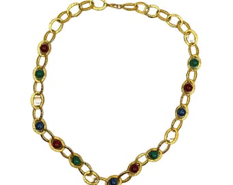 May include: A gold-toned necklace featuring a textured chain design. The necklace is adorned with alternating colorful gemstones in red, green, and blue. The necklace is displayed against a white background.
