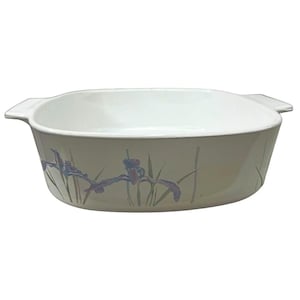 May include: Off-white rectangular baking dish with a floral iris design in purple and green. The dish has two handles and a white interior. A classic piece for baking and serving.