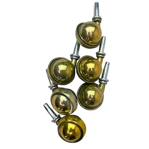 May include: A collection of six antique brass casters with silver-colored stems. Each caster features a spherical brass wheel and a cylindrical stem for attachment. The casters are designed for furniture and provide mobility.