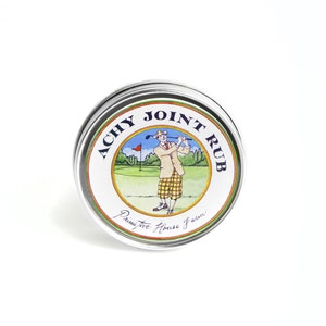 Puede incluir: Una lata de plata con una etiqueta blanca que dice "Achy Joint Rub" en letras azules y verdes. La etiqueta también presenta un dibujo animado de un golfista con un atuendo verde, blanco y amarillo en un campo de golf.
