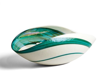 May include: A white glass bowl with a wavy, organic shape. The bowl has green stripes and a glossy finish.