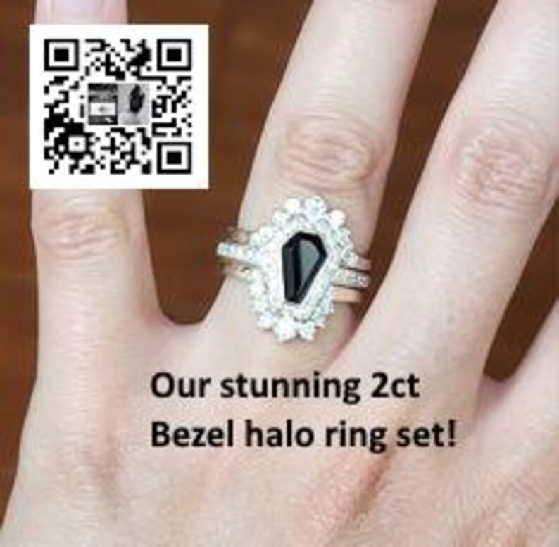 May include: A three-piece ring set featuring a black gemstone in a coffin-shaped setting surrounded by a halo of clear stones. The set includes a thin band and a wider band with a textured finish.