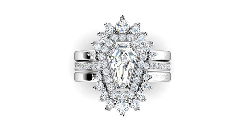 May include: A silver ring set with a large, clear, octagon-shaped diamond surrounded by smaller diamonds. The ring is set on a band with a delicate diamond-studded design.
