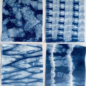 May include: Four square fabric swatches with different blue tie-dye patterns. The patterns include a swirling design, a striped design, a wavy design, and a vertical stripe design.