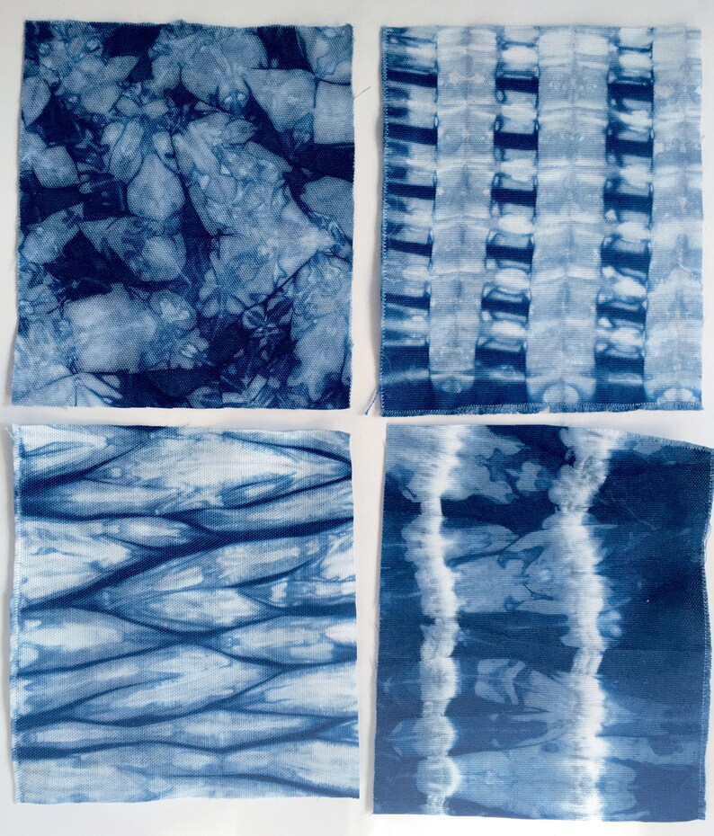 May include: Four square fabric swatches with different blue tie-dye patterns. The patterns include a swirling design, a striped design, a wavy design, and a vertical stripe design.