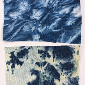 May include: Two pieces of blue denim fabric with a tie-dye pattern. The top piece has a darker blue color and a more abstract pattern. The bottom piece has a lighter blue color and a more floral pattern.