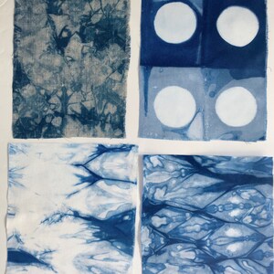 May include: Four fabric squares with different blue dye patterns. The top left square has a blue and white abstract pattern. The top right square has two rows of two white circles on a blue background. The bottom left square has a blue and white abstract pattern with a white background. The bottom right square has a blue and white abstract pattern with a white background.