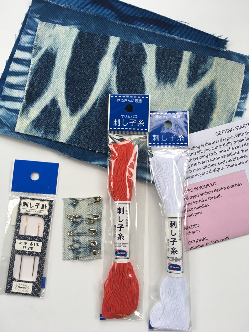 May include: A sashiko embroidery kit with two spools of thread, one red and one white, a pack of needles, safety pins, and two denim patches. The packaging is labeled in Japanese with the text "Sashiko Thread" and "Sashiko Needle".