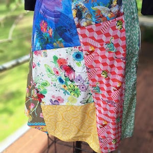 May include: A colourful patchwork skirt featuring a range of floral, geometric and abstract patterns. The skirt is made from different fabrics sewn together, creating a unique and eye-catching design.