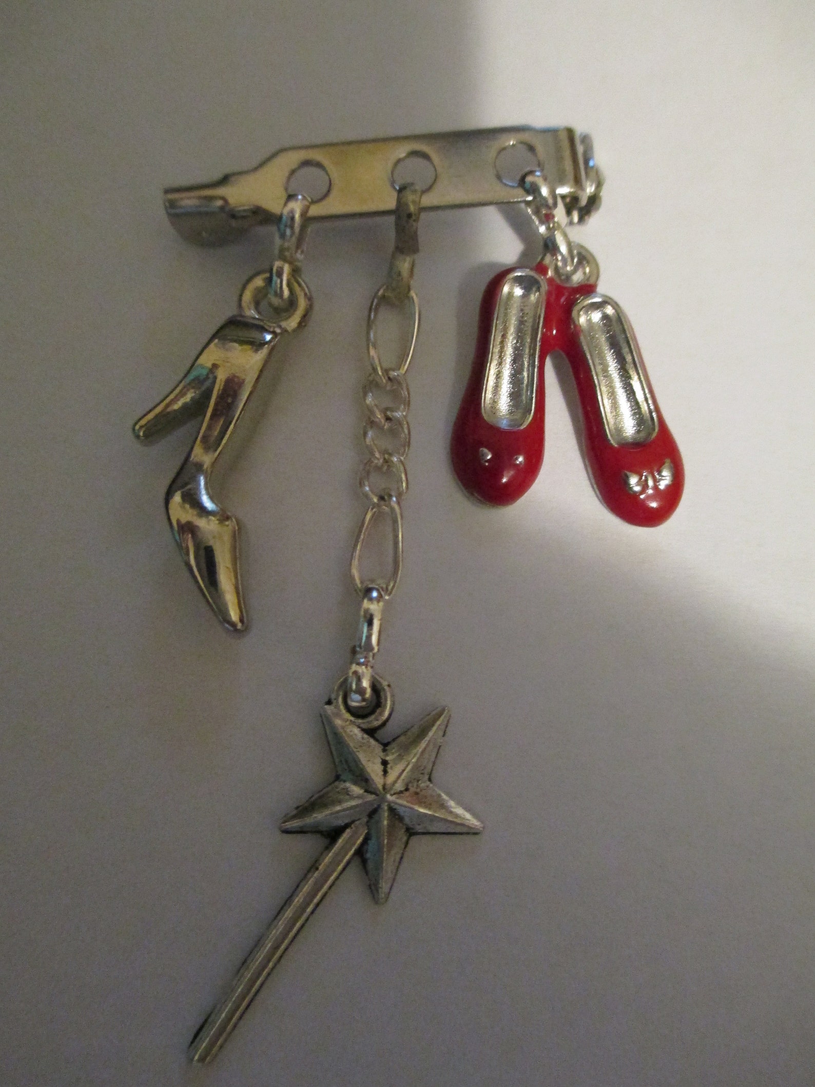 a brooch for fans of dorothy in wizard of oz, cinderella, ballet dancing, fairies,. red enamelled shoes, fairie/angle wand, sing