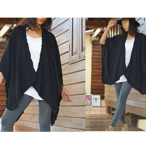 K&ouml;nnte beinhalten: Ein schwarzer Baumwoll-Kimono mit ausgefransten Kanten. Der Kimono ist vorne offen und hat eine lockere Passform. Das Model tr&auml;gt graue Leggings.