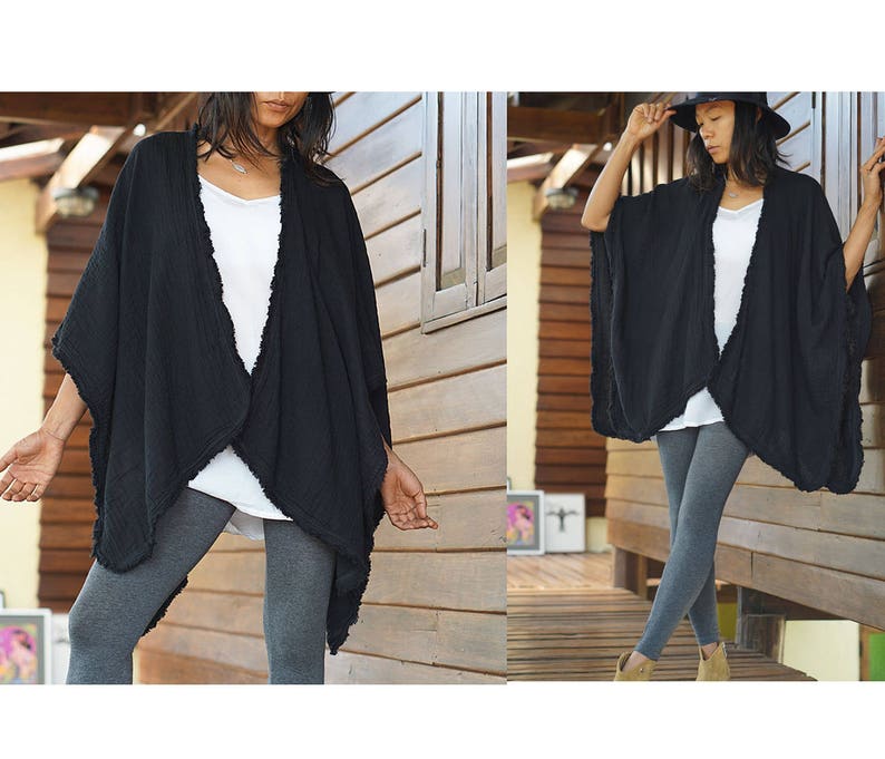 K&ouml;nnte beinhalten: Ein schwarzer Baumwoll-Kimono mit ausgefransten Kanten. Der Kimono ist vorne offen und hat eine lockere Passform. Das Model tr&auml;gt graue Leggings.
