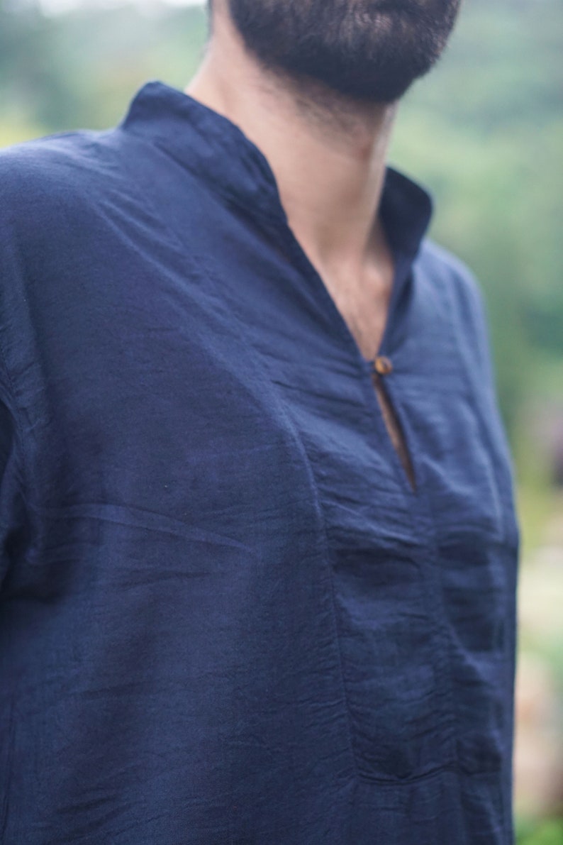 May include: A dark blue, long-sleeved shirt with a v-neck and a single button closure.
