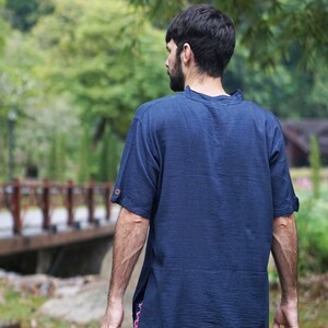 May include: A person wearing a dark blue short-sleeved shirt with a collar. The shirt has a relaxed fit and is made of a soft, comfortable fabric.