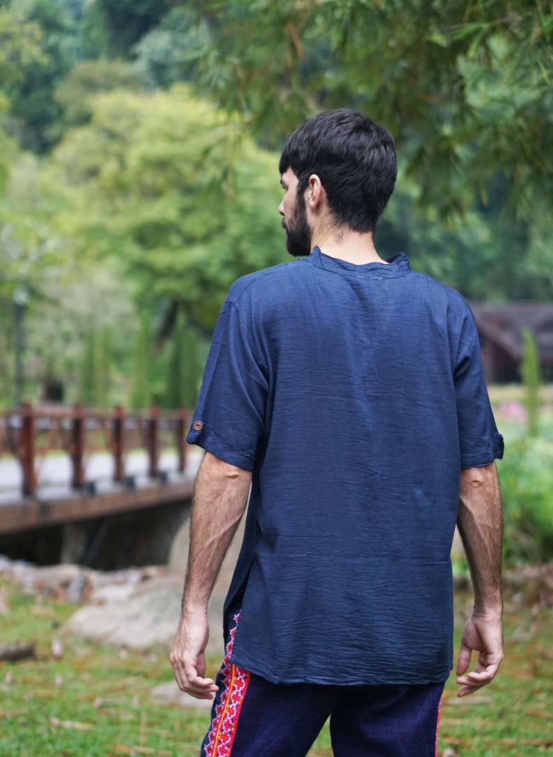 May include: A person wearing a dark blue short-sleeved shirt with a collar. The shirt has a relaxed fit and is made of a soft, comfortable fabric.