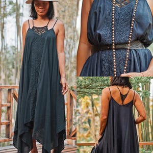 Op de afbeelding: Een zwarte maxi-jurk met spaghettibandjes en een lijfje met kant. De jurk heeft een asymmetrische zoom en wordt gedragen met een hoed met brede rand. De jurk is gemaakt van een lichte stof, ideaal voor warm weer.