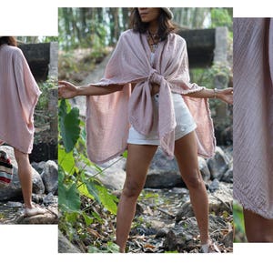 May include: A pink cotton gauze kimono with a frayed edge. The kimono is tied at the waist and worn over white shorts.