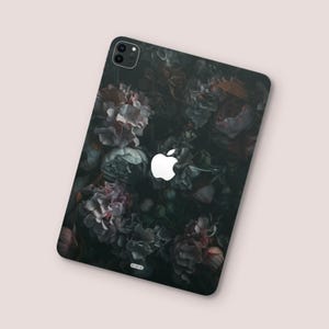 Pode incluir: Uma capa de telefone preta com um padrão floral escuro e um logotipo da Apple branco.