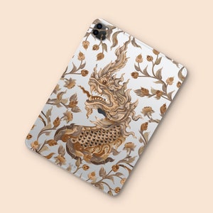 May include: A white phone case with a brown and gold design featuring a mythical creature with intricate details and floral patterns.