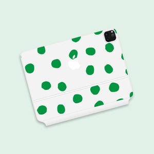 May include: White phone case with a green polka dot pattern. The case has a cutout for the camera lens and a white Apple logo.