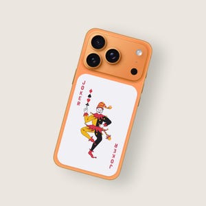 Puede incluir: Funda de teléfono naranja con un diseño de carta de juego Joker. La carta muestra un bufón en amarillo, negro y rojo, sosteniendo un símbolo de palo. La palabra "JOKER" está impresa verticalmente en ambos lados de la carta.