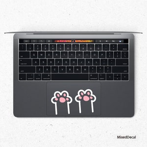 May include: A gray laptop computer with a black keyboard and a trackpad with two pink paw print stickers.