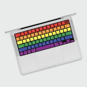 May include: A laptop computer with a rainbow keyboard cover. The keys are labeled with the letters of the alphabet, numbers, and symbols.