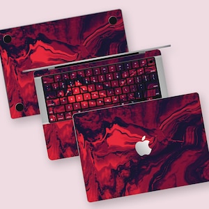 May include: A laptop skin with a red and black abstract marbled design. The skin covers the top, bottom, and keyboard of the laptop. The Apple logo is visible on the bottom skin.