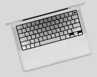 Może przedstawiać: Srebrny laptop z czarną klawiaturą i gładzikiem. Klawiatura ma białe tło z czarnymi klawiszami i czarnymi napisami.