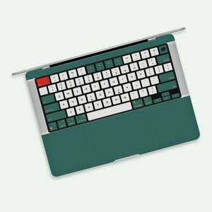 Puede incluir: Un ordenador portátil verde con un teclado blanco y un trackpad negro. El teclado tiene letras doradas.