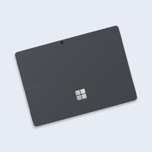 May include: A dark grey tablet computer with a silver Microsoft logo on the back. The tablet has a front-facing camera and a thin black bezel.