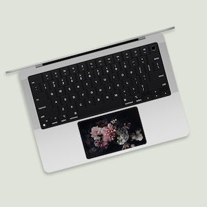 May include: A silver laptop computer with a black keyboard and a floral design on the touchpad.