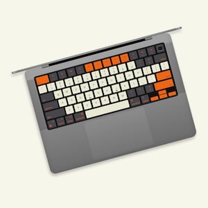 May include: A gray laptop computer with a black keyboard and a trackpad. The keys are labeled with white letters and orange accents. The laptop is closed.