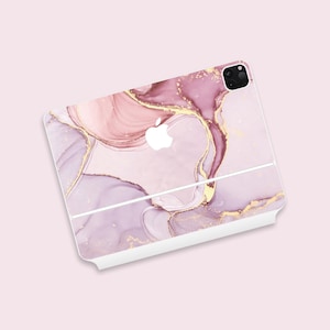 May include: A white phone case with a pink and gold marble design. The case has a cutout for the camera lens and the Apple logo.