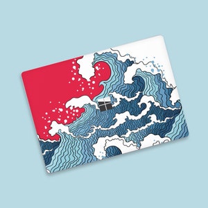 Op de afbeelding: Een laptop skin met een rode en witte achtergrond met een blauw en wit golfontwerp. Het golfontwerp doet denken aan traditionele Japanse kunst.