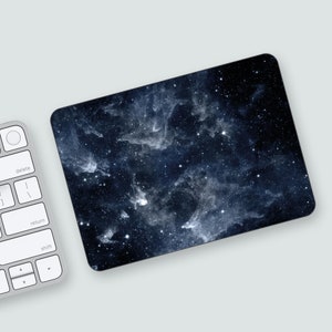 May include: A dark blue laptop skin with a galaxy design featuring white and light blue clouds and stars.
