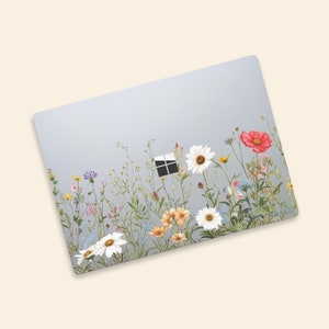 May include: A light blue laptop skin with a floral design. The design features a variety of flowers, including daisies, poppies, and wildflowers, in shades of pink, red, yellow, and white. The flowers are arranged in a row along the bottom of the skin, with a small window cutout in the center.