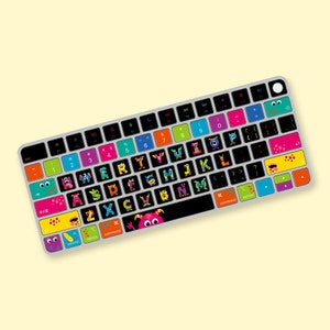 Könnte beinhalten: Eine Tastatur mit bunten Monsterstickern auf den Tasten. Die Sticker zeigen Buchstaben des Alphabets und einige Satzzeichen. Die Tastatur ist grau und hat eine schwarze obere Reihe mit Funktionstasten.