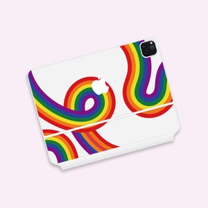 Puede incluir: Carcasa de teléfono blanca con un diseño de arcoíris. La carcasa tiene un recorte para el objetivo de la cámara y un logotipo de Apple blanco.