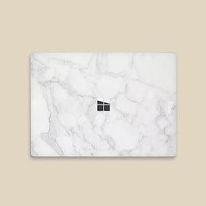May include: White laptop skin with a marble pattern and the Microsoft Windows logo in the center.